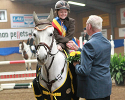 Kreisreiterbundvorsitzender Hans-Joachim Richter gratulierte die neuen Hallen-Kreismeister, zu denen im Springen der Junioren in Klasse E auch Lilli Plath aus Timmendorf mit Pony Little Gone zählte. Foto: Wego