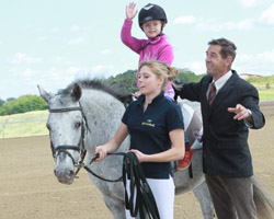 Nova Rave, Tochter von Franja Pon, Inhaberin des Gutes Vorbeck, durfte mit Pony Flora in Begleitung ihrer Reitlehrerin Maria Drenseck und Betriebsteilleiter Norbert Lissak als Erste auf den neu entstandenen Turnierplatz. Foto: Wego
