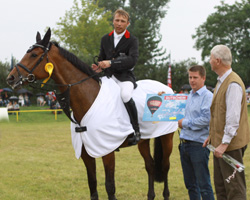 Turnierleiter Ingo Meißner und Bürgermeister Hermann Oldemeyer gratulieren Philipp Schober zum Sieg im Großen Preis. Foto: Wego