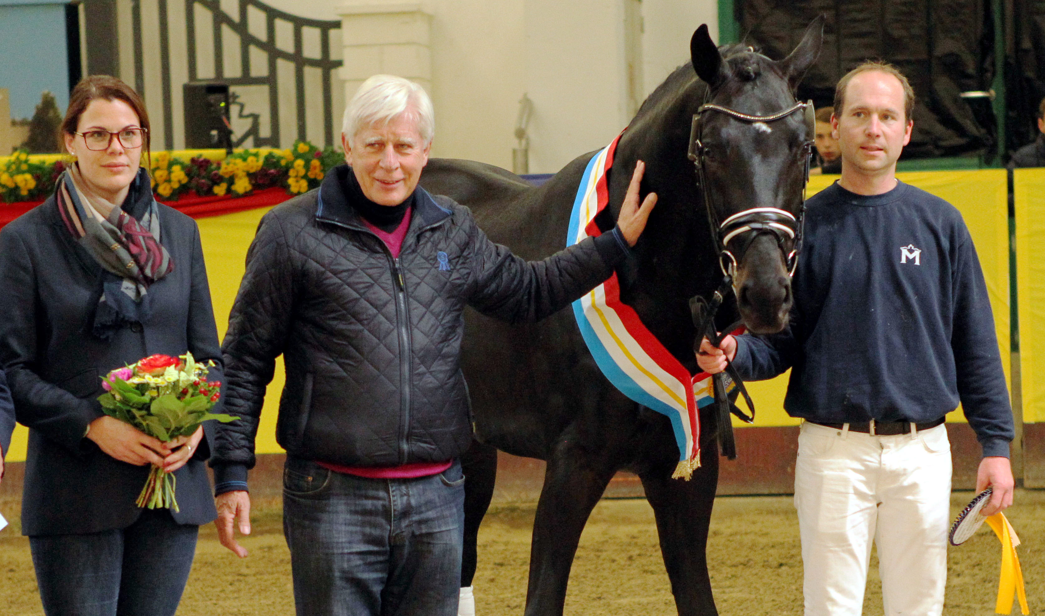 Paul Schockemöhle an seinem Siegerhengst von Fürstenball / Zonik /Sir Donnerthall I / Don Schufro (vorgestellt von Christoph Hinkel), den er selbst im Gestüt Lewitz aufstellt. Zuchtleiterin und Geschäftsführerin Karoline Gehring vom Verband der Pferdezüchter MV gratuliert. Foto: Jutta Wego