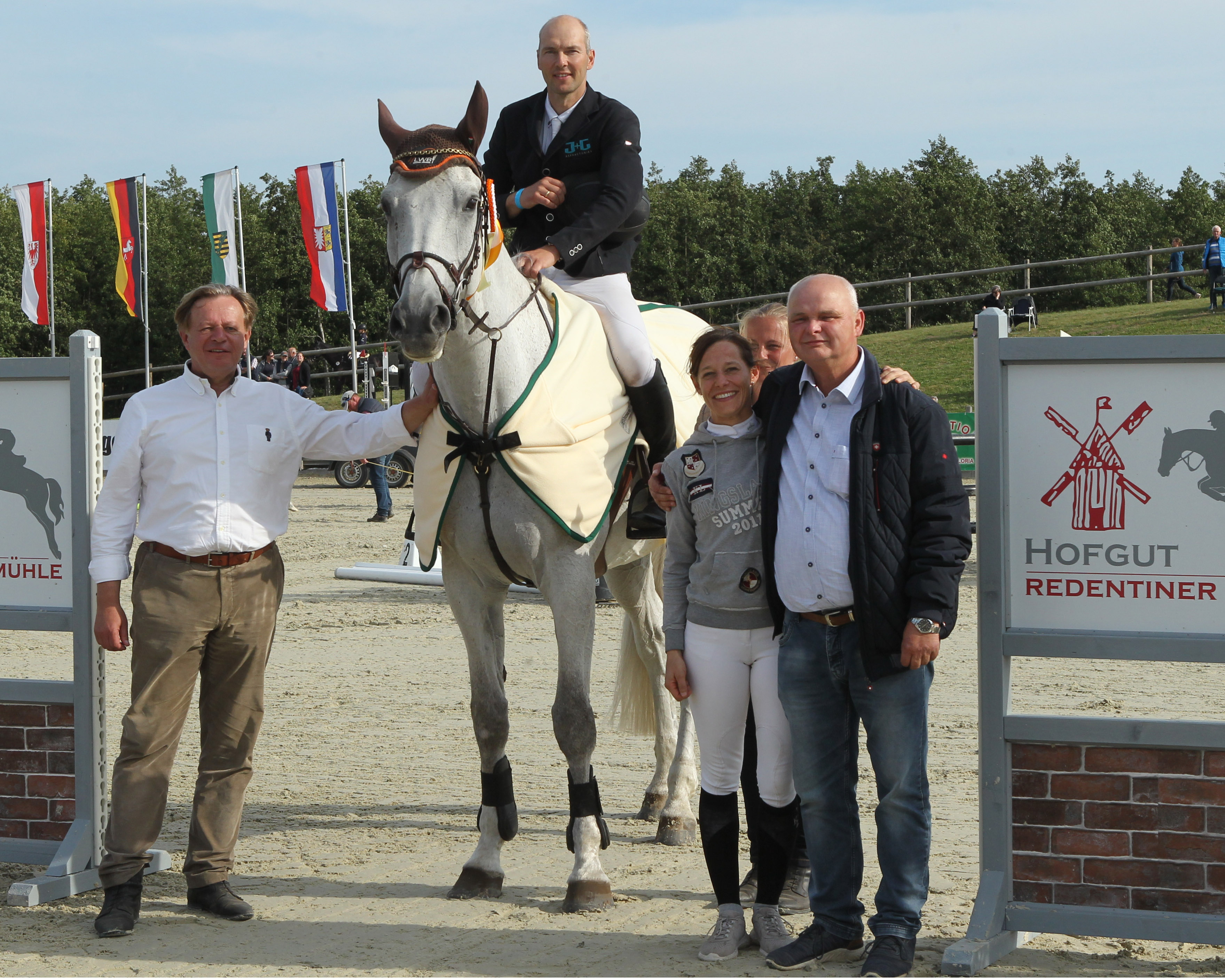 Sponsor Andreas Neumann von der Vorpommern Ausbau Gesellschaft (r.), Turnierleiterin Kathrin Wiedmer und ihr Vater Peter Leibold gratulieren Ulf Ebel zum Sieg im Großen Preis. Foto: Jutta Wego