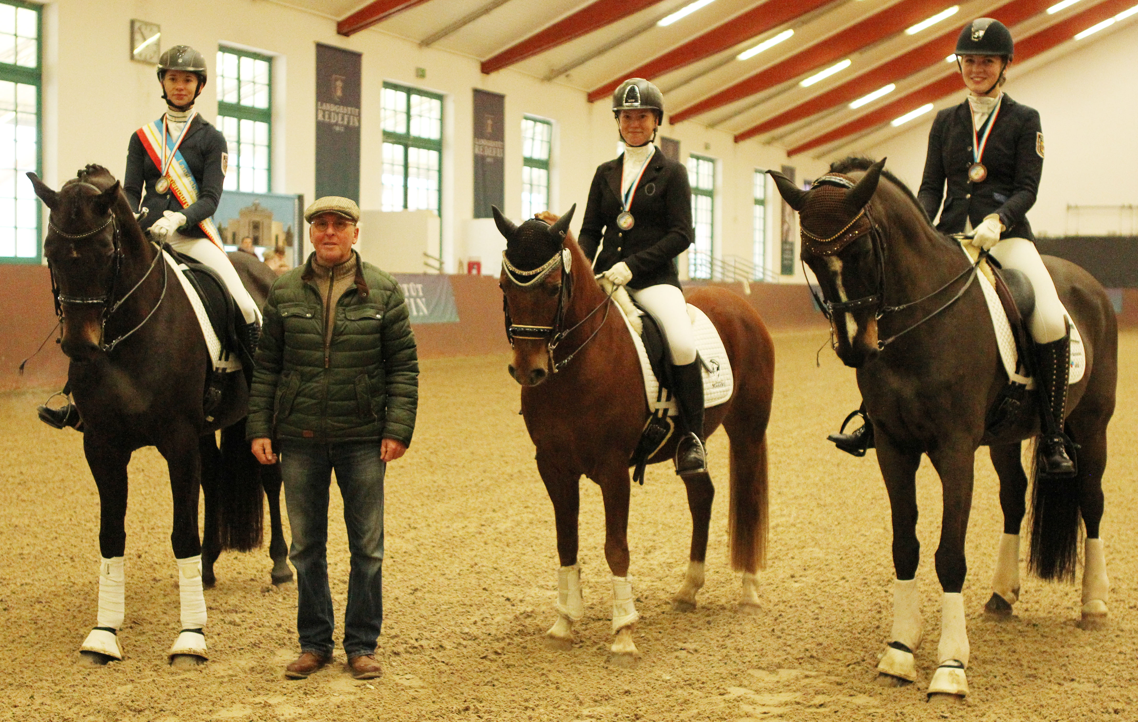 Die Medaillengewinner der Championatsklasse M werden von Honorartrainer Michael Thieme gratuliert: Christina Romanowski, Stülow (Gold), Ann-Christin Mehl, Zingst (Silber) und Antonia Kurp, Rostocker Heide (Bronze. © Jutta Wego