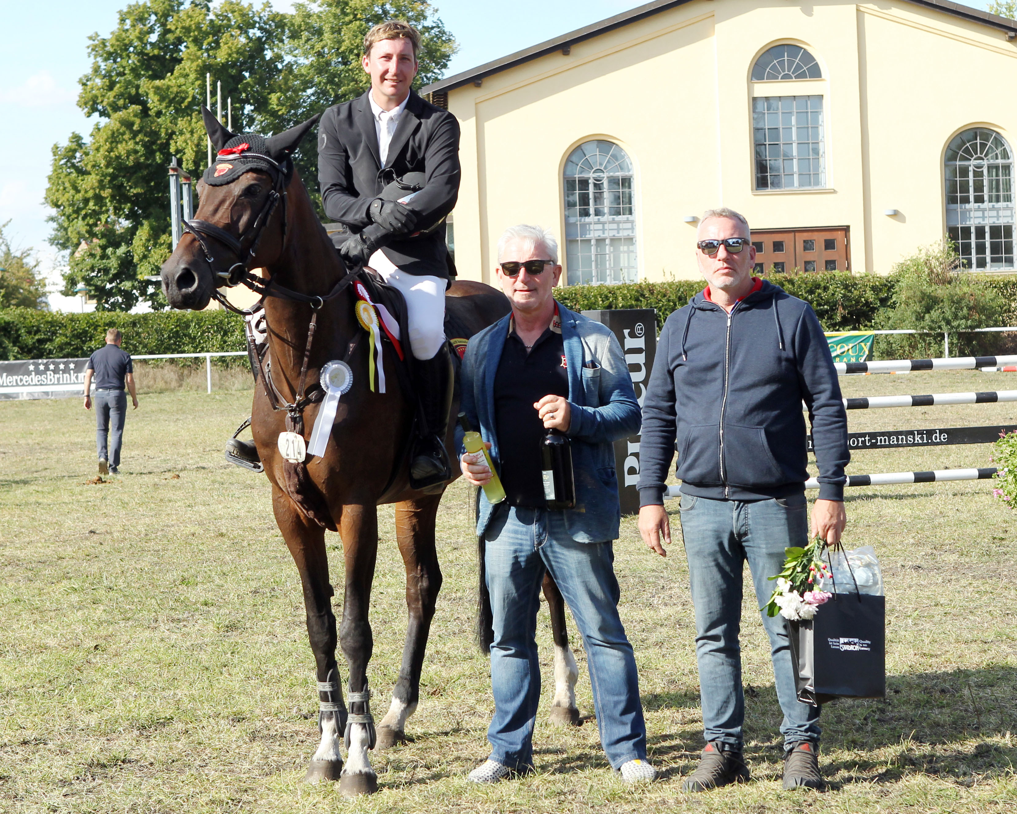 Maik Walter (r.) GF von Logistik-Rosenow, selbst einst erfolgreicher Springreiter, und der Vertreter der Weinfirma Pallhuber, gratulieren Paul Wiktor zum Sieg im Großen Preis. © Jutta Wego