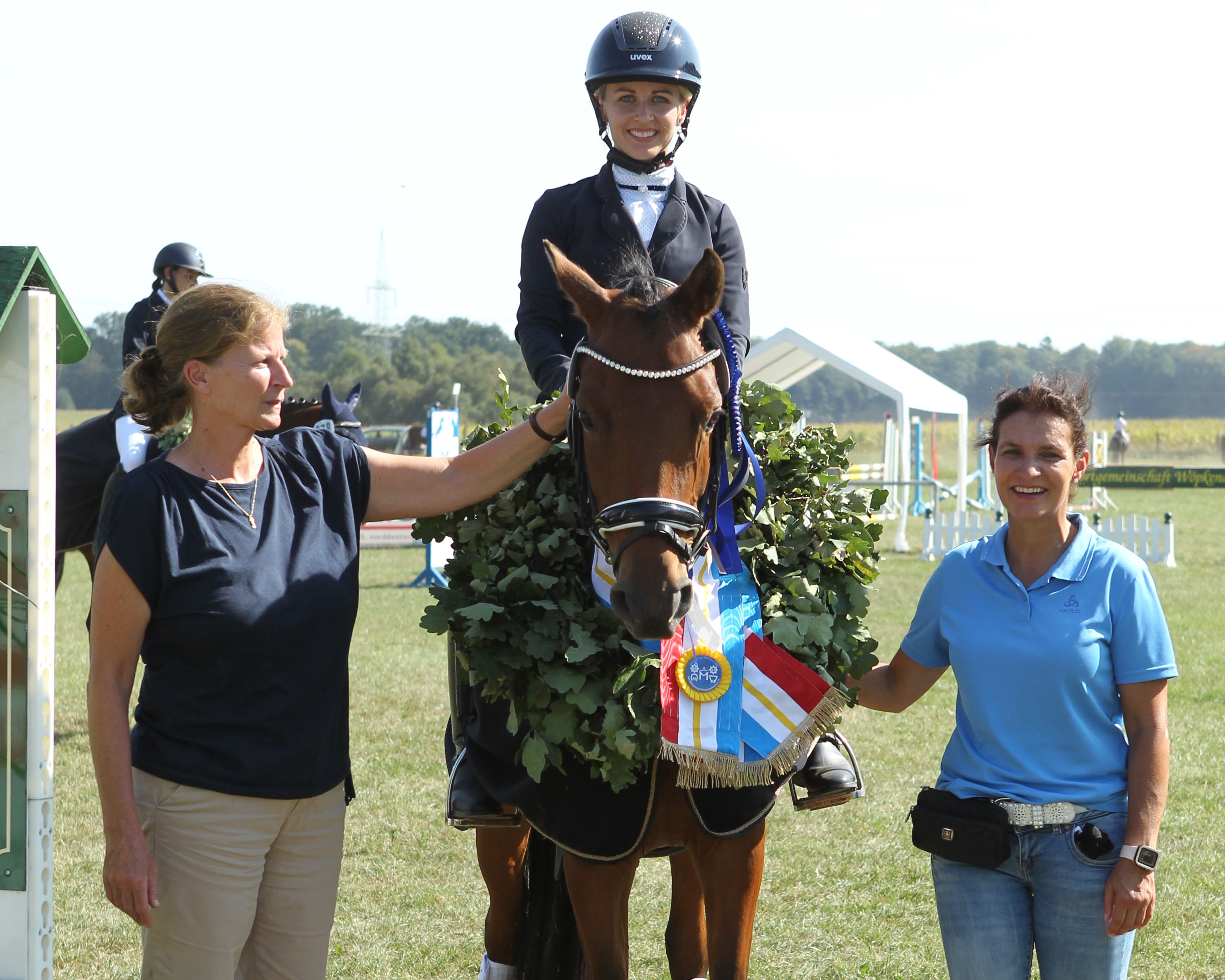 Präsidiumsmitglied Sandra Engelmann (r.) und Verbandsprokuristin Heike Fischer gratulieren Marie Kirchner zum Sieg von Djosefine G im Championat der Reit- und Dressurponys. © Jutta Wego