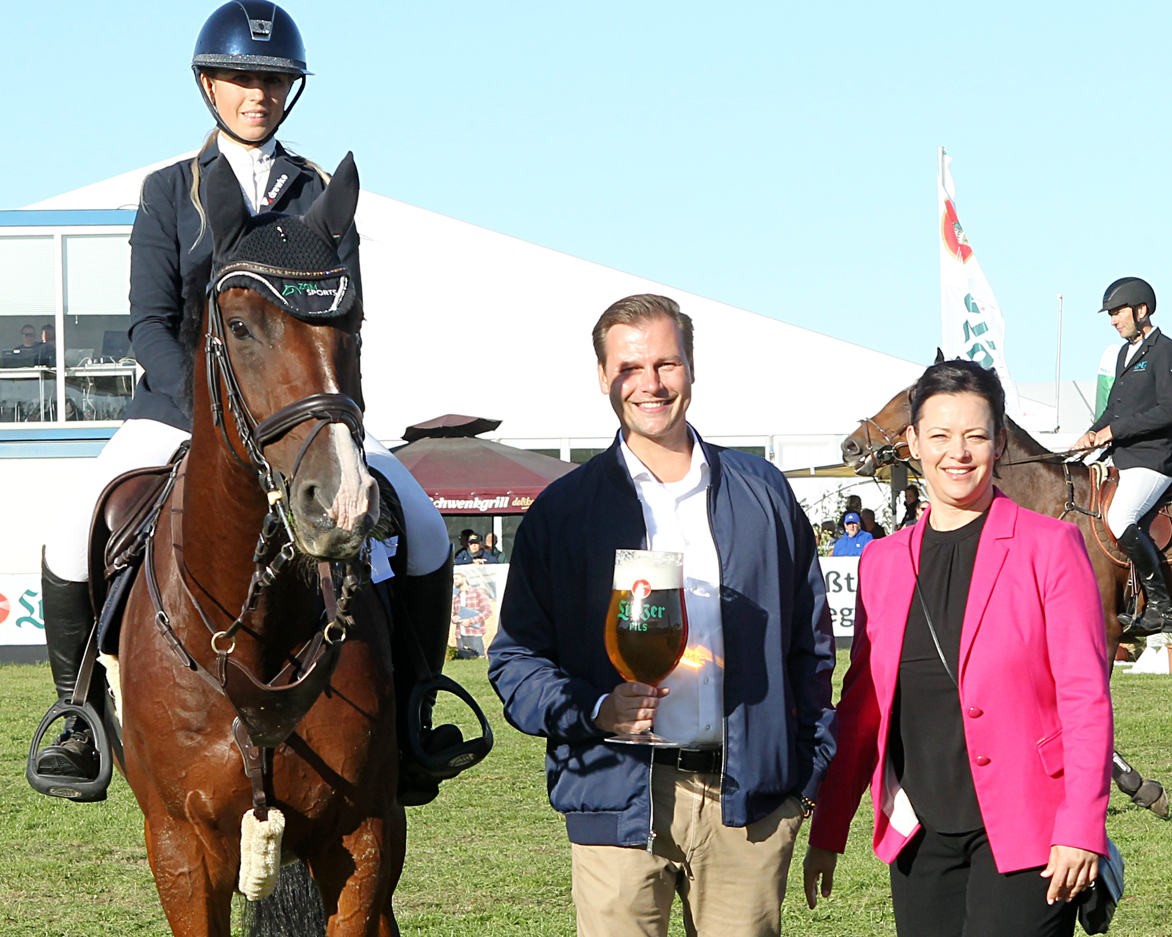 Sascha Mütel von der Brauerei Lübz, die seit 1991 ohne Unterbrechung am Sponsoring des Großen Preises beteiligt ist, gratuliert Christin Wascher in Begleitung von Turnierleiterin Christin Mondesi zum 3. Platz. © J.Wego