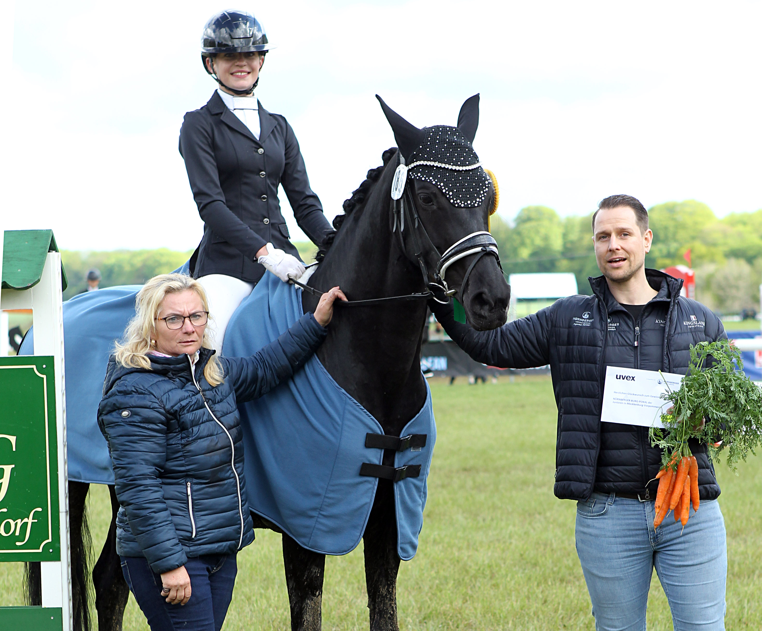 Mit Wertnote 9,0 hat Matilda Behrens (RFV Eldena) die Dressurreiterprüfung zur Qualifikation für den Nürnberger-Burg-Pokal der MV-Junioren bis 16 gewonnen. Sponsor Normen Femfert und Turnierleiterin Birca Roos gratulieren. © J. Wego