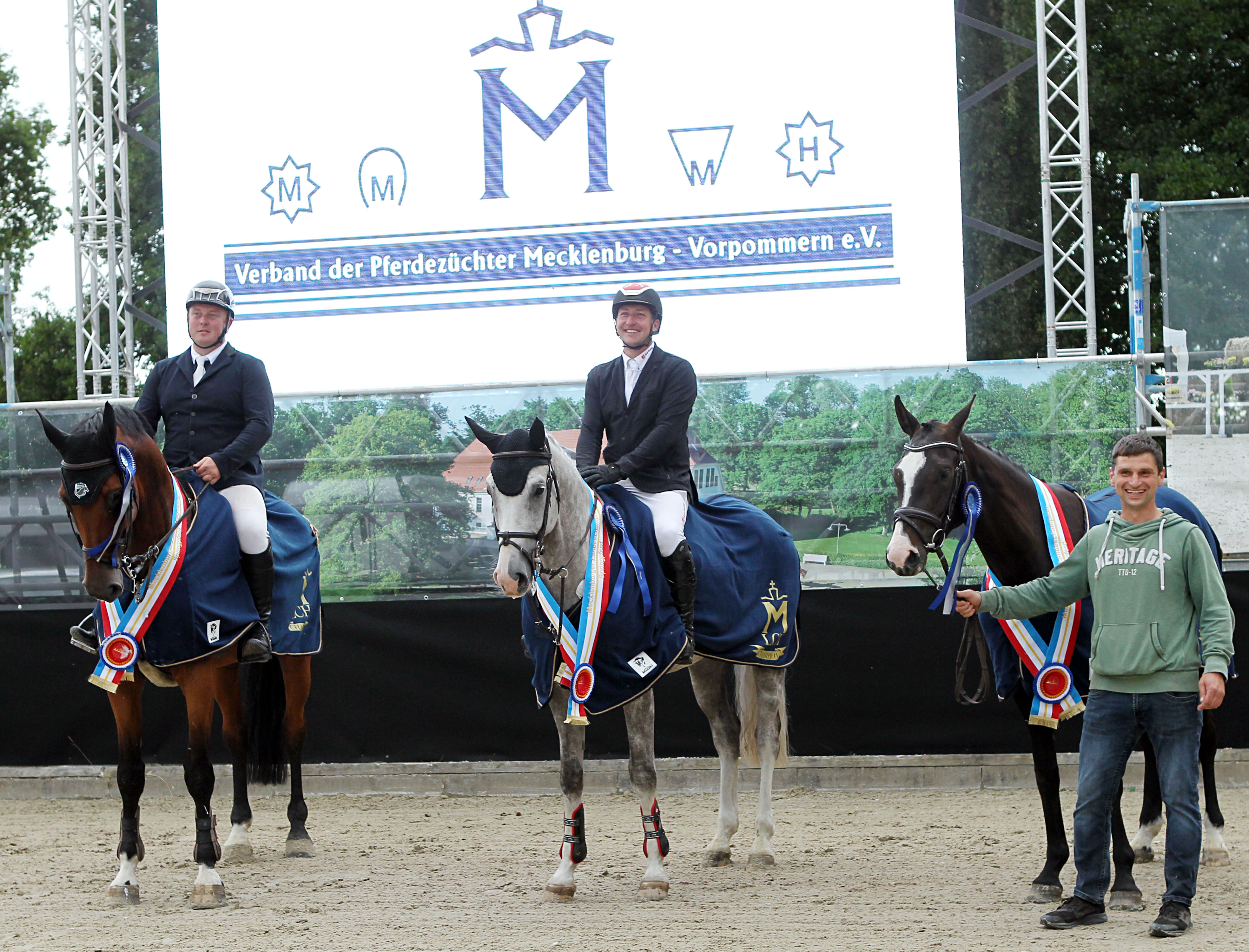 Die drei neuen Mecklenburger Springchmpion des Jahres 2025: v.r. die 4-jährige Summer LK (v. Sandro Junior x Cero I) mit Züchter Lars Köhler; der 5-jährigen Cacique (v. Cellestial x I do It) mit Paul Wiktor und der 6-jährige Cerados B (v. Cero Michel x Lordanos) mit Christoph Maack. © J. Wego