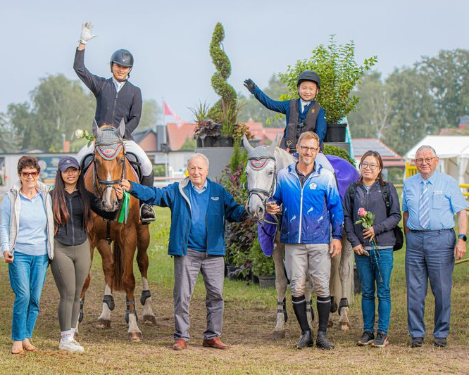 Helga (l.) und Volker Tonn (Mitte) kamen nach Blowatz um ihren Dohn Markus zu sehen (r. neben dem Schimmel), der seit 10 Jahren Trainer in Taiwan ist und mit seinem Team am Turnier in Blowatz teilnahm. Der 11-jährige Riu Huang hat auf dem Schimmel Caramella ein Zwei-Sterne A-Springen in bestem Stil gewonnen. Franz Wego (r.) überreichte ihm die Schleife. S. Boge