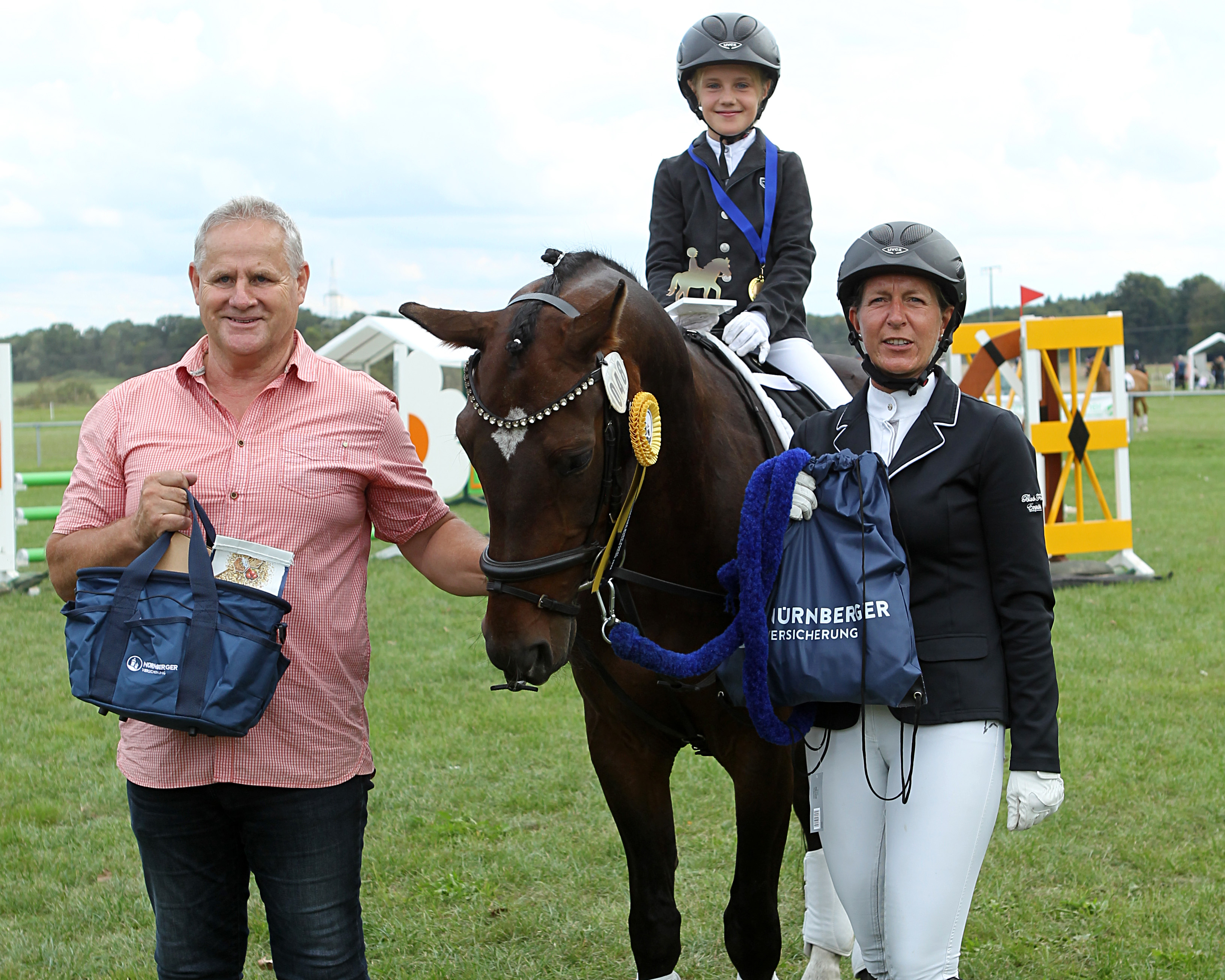 Die Siegerin im Finale des NÜRNBERGER Führzügel-Pokals, Friederike Derer von der RSG Wöpkendorf auf El Chico mit An na Grawe, Besitzerin von El Chico und dem Vater von Norman Femfert, der in dessen Vertretung die Finalisten beglückwünschte. © J. Wego