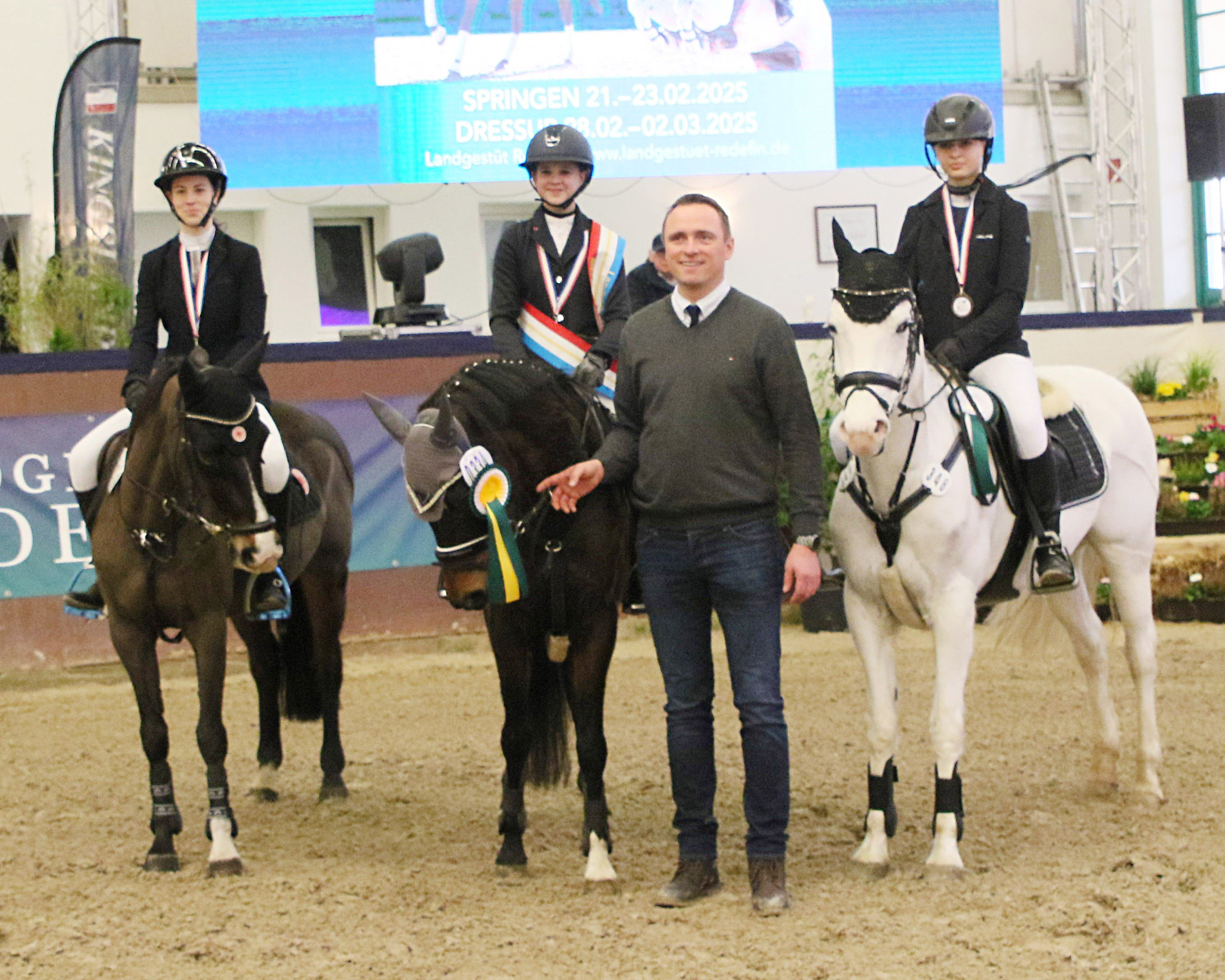 Heiko Strohbehn gratuliert die Medaillengewinner der Pony-Springreiter beim Landes-Hallenchampionat 2025: v.l. Elli Mau (Ahlbeck), Fiby Sosna (Tenze), Tessa Kaminski (Plöwen). © KaLo