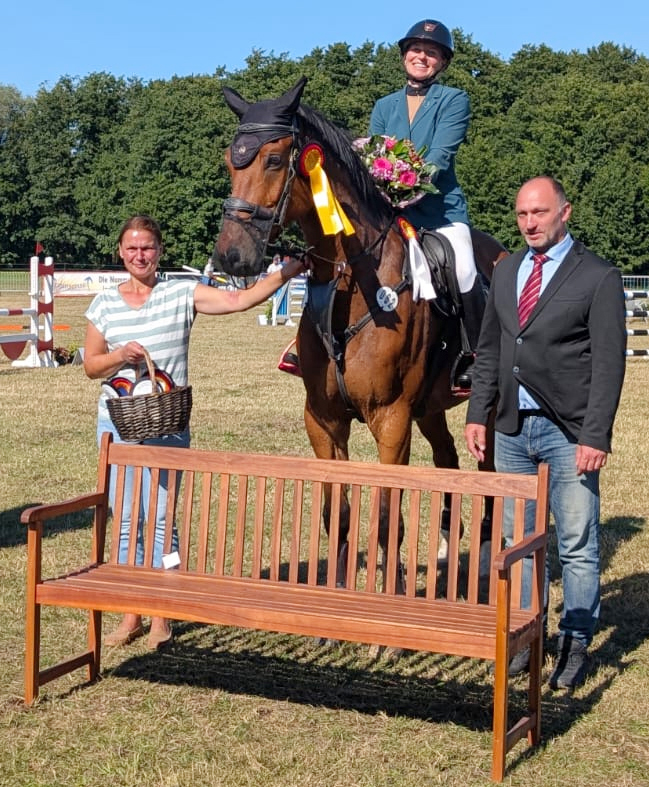 Turnierleiterin Ute Friesecke und Richter Stefan Bartel gratulieren Juliane Weihs zum Sieg die sich über eine Gartenbank als Ehrenpreis und über einen Sondergeldpreis freuen konnte. © RFV Waterkant Kühlungsborn